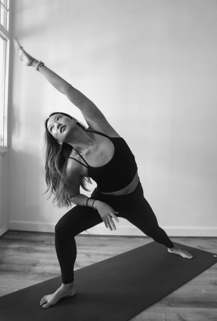 A teacher in a side angle stretch by the studio window.