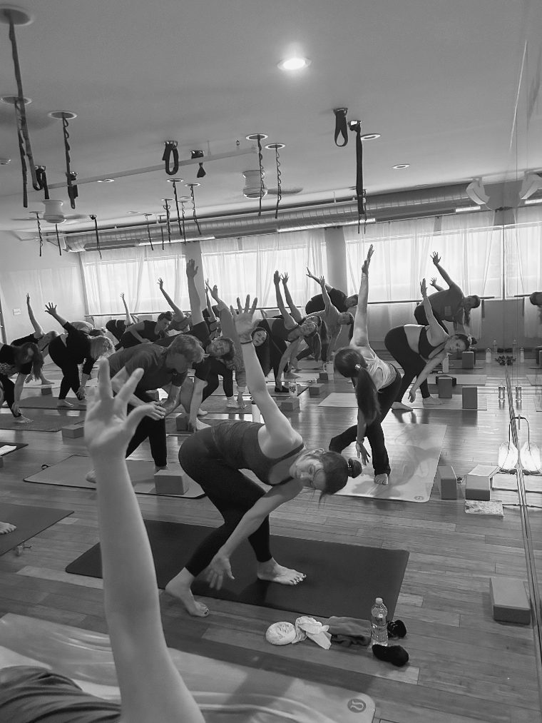 A full class reaching into a side angle, arms raised toward the windows.